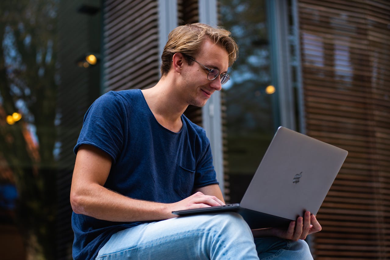 services-03 A young man sitting outdoors in Leiden, Netherlands, working on a laptop.